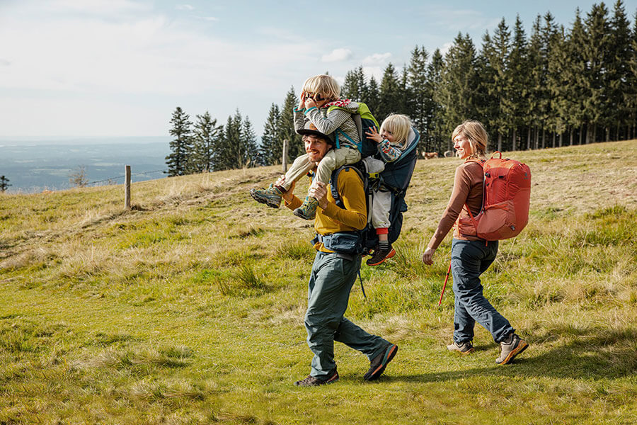 Familie mit zwei Kindern und Kindertrage unterwegs im Mittelgebirge