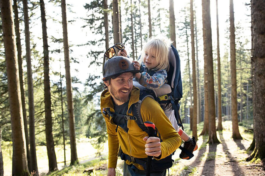 Vater mit Kind in Kindertrage im Wald unterwegs